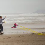 A person flies a brightly colored butterfly kite on Rockaway Beach.